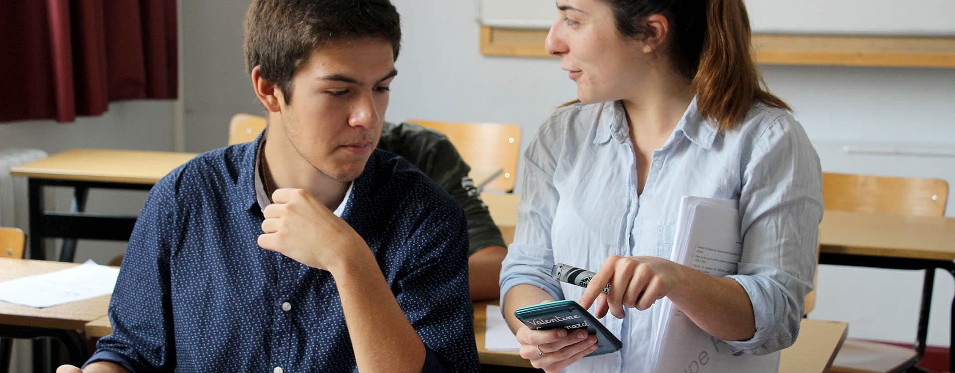 Prof aidant un élève à la fin d’un stage de vacances